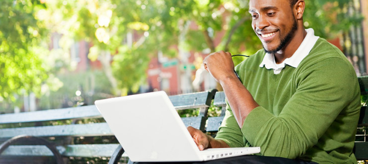 Young man on park bench with laptop
