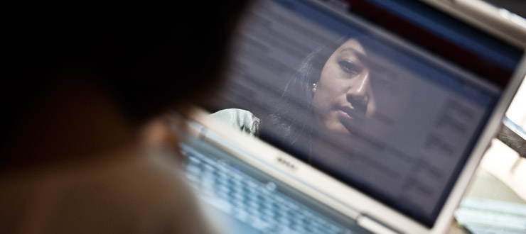 Student's reflection on a laptop screen