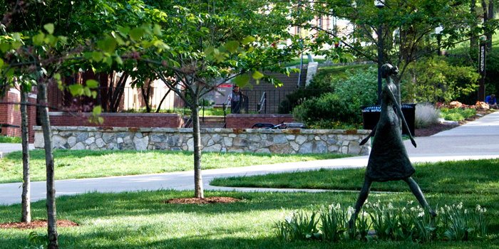Photo of a statue of a woman walking on campus.