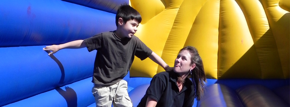 #caption2 Playing in the Bouncy House - A communication disorders graduate student interacts with children as they play in the bouncy house at the Clinical Education Complex Summit