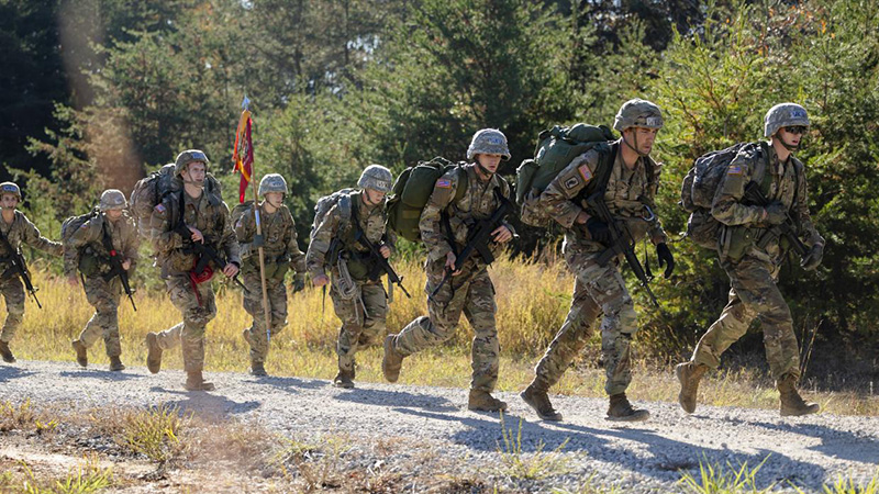 WKU ROTC Cadets move to their next station in the Brigade Ranger Challenge at Fort Knox, Kentucky on Saturday, Nov. 2. WKU’s ROTC is a part of the 7th Brigade. (Photo by Lauren Howe) WKU Army ROTC cadets marching in formation across an open field carrying the red Hilltopper Battalion guidon flag.