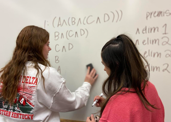 Two people working on a symbolic logic problem.