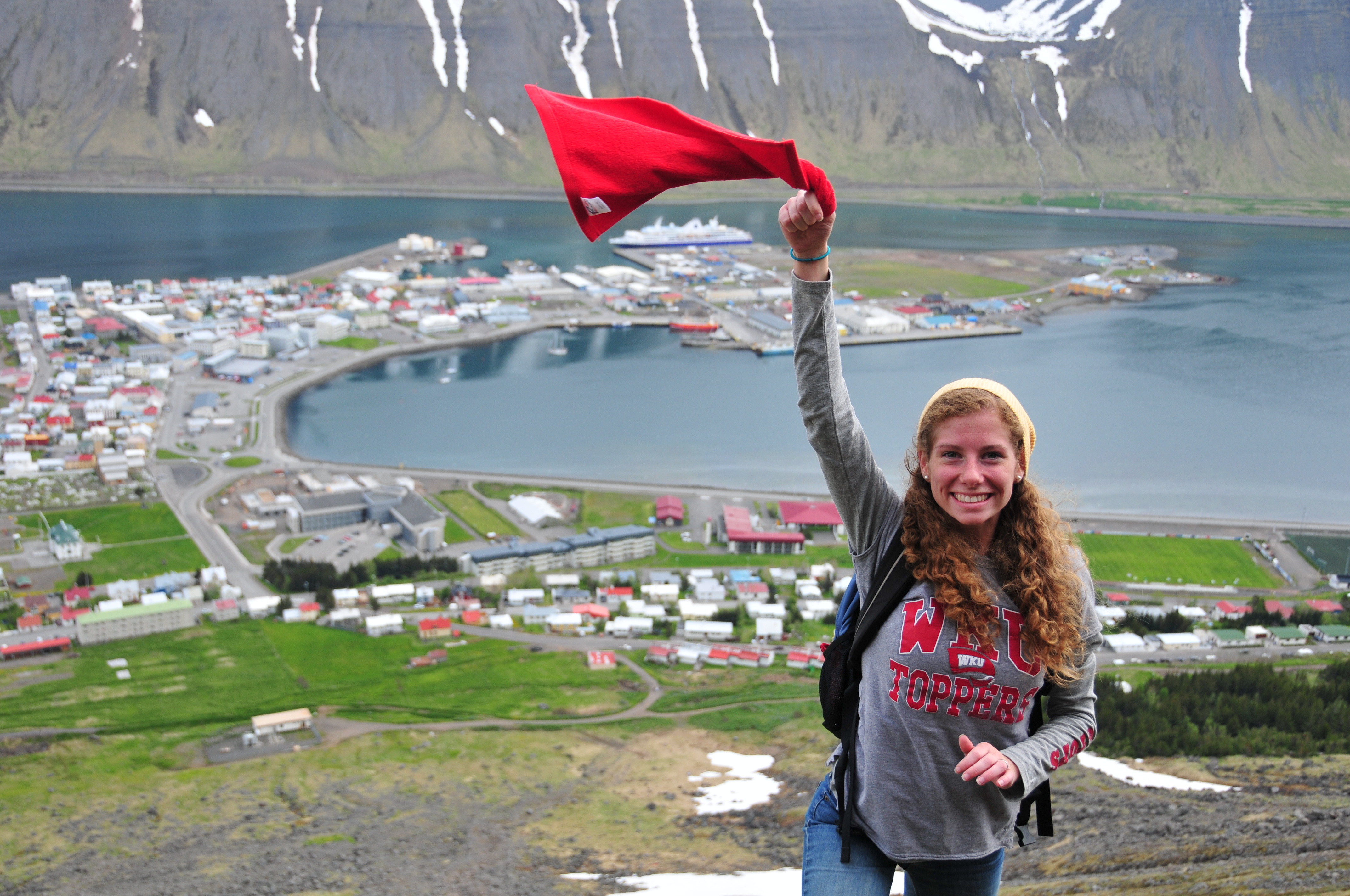 WKU student waves red towel while studying abroad.