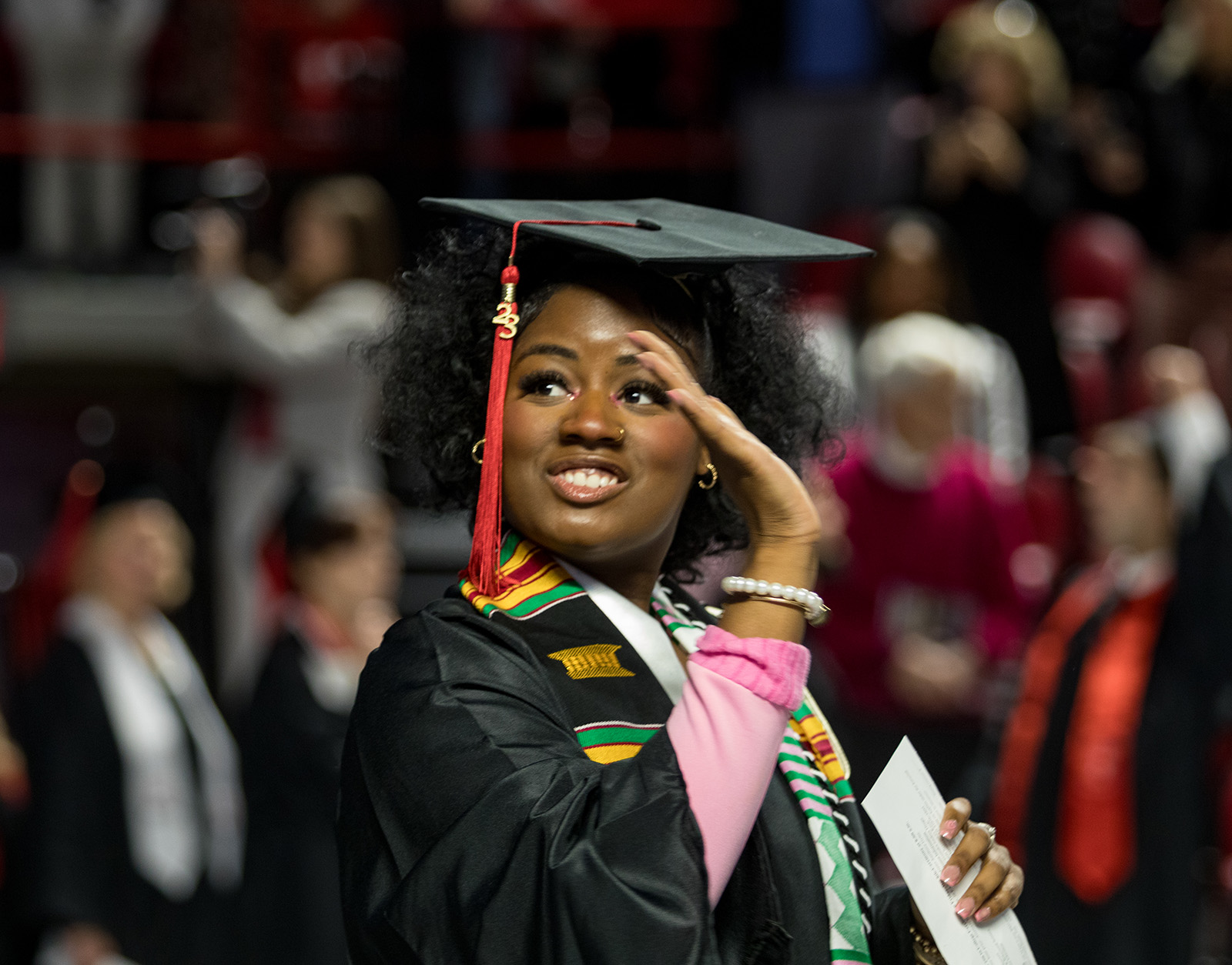 A student graduating during fall commencement with a degree in hand.