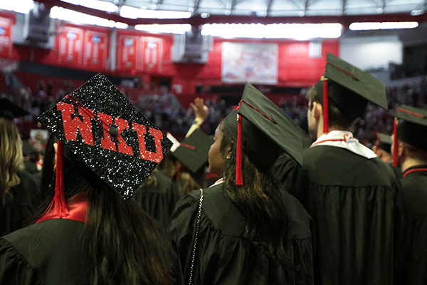 WKU graduates standing in a line with decorated cap spelling out WKU