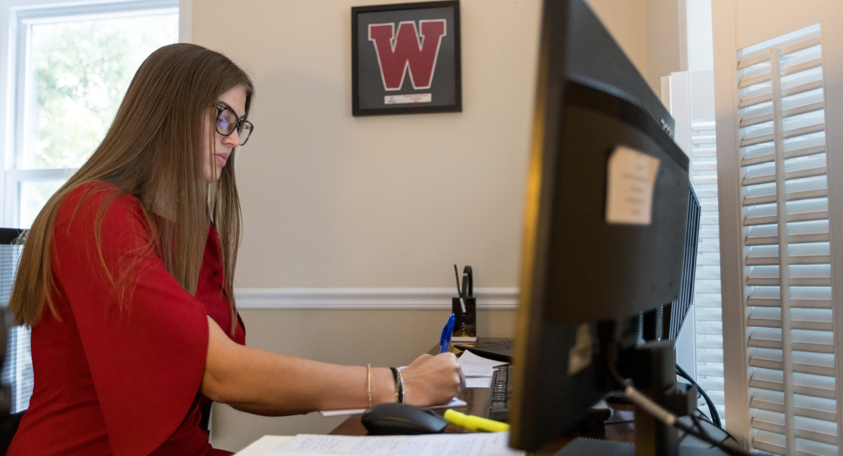 A Western Kentucky University alumnus sits at a desk and writes on a piece of paper.