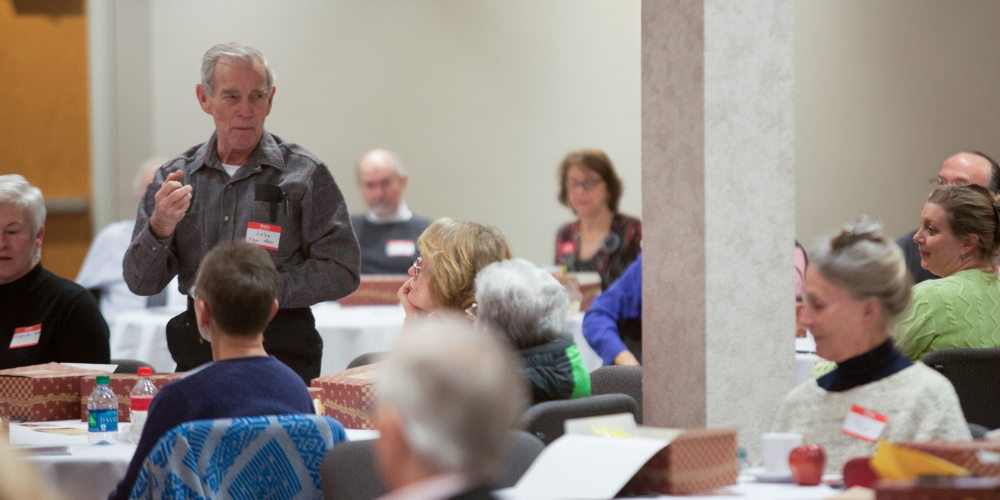 A member of Society of Lifelong Learning at WKU stands up to talk at an event.