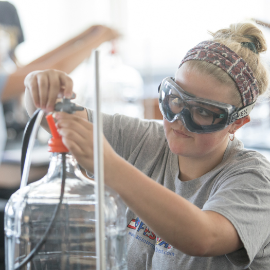 A WKU student wearing lab goggles works in a Chemistry lab.