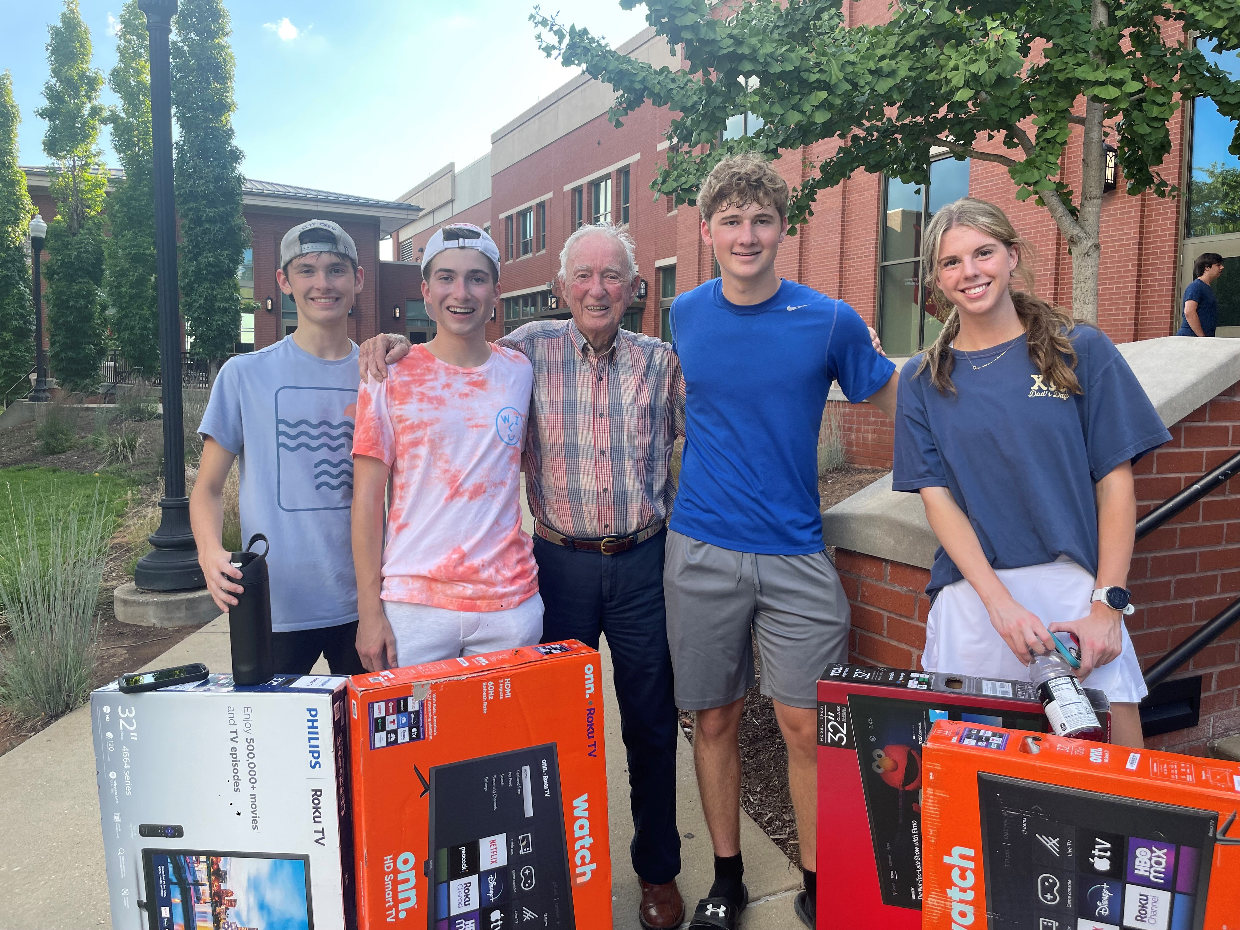 J. Lee Robertson (middle) smiling with students at Amazing Big Red Race social and prizes