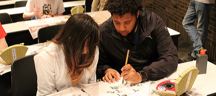 A student helping astudent learn to write Chinese