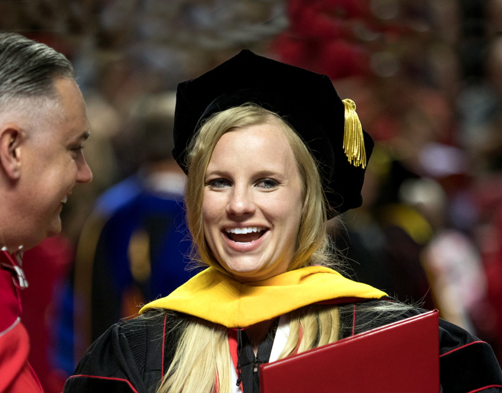 A student graduating during fall commencement with a degree in hand.